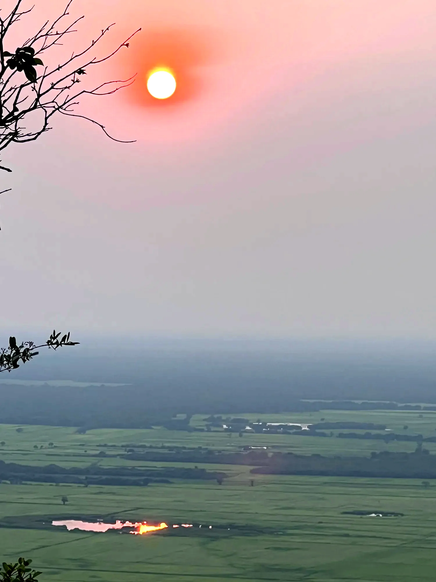 Soleil rouge se couchant sur une plaine, au loin